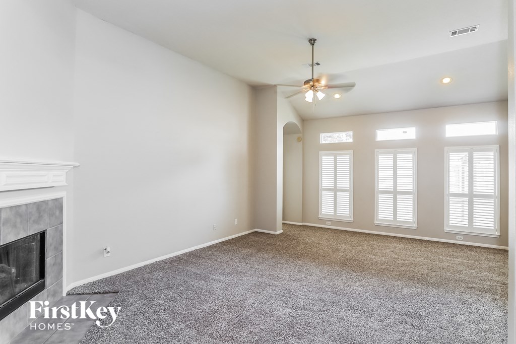 A spacious living room with a fireplace and a ceiling fan.