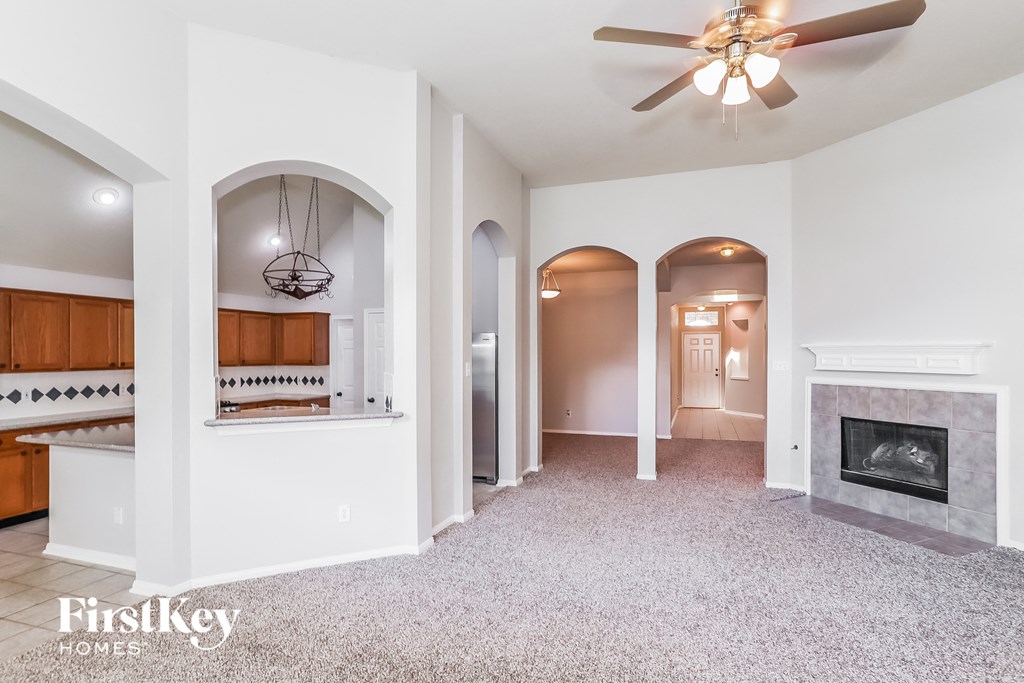 A spacious living room with a fireplace and a ceiling fan.