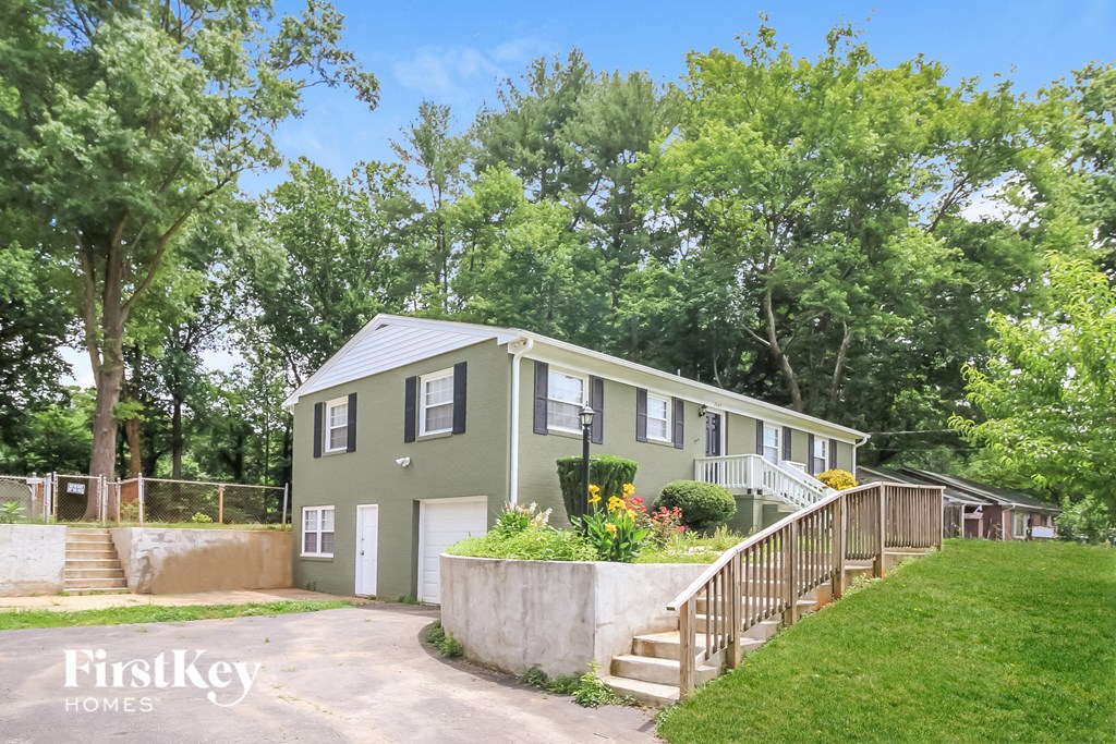 a green house with a staircase and a yard with trees