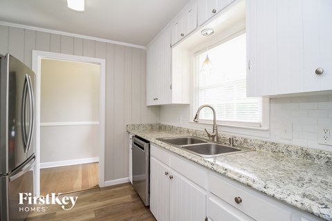 a kitchen with white cabinets and a sink and a window