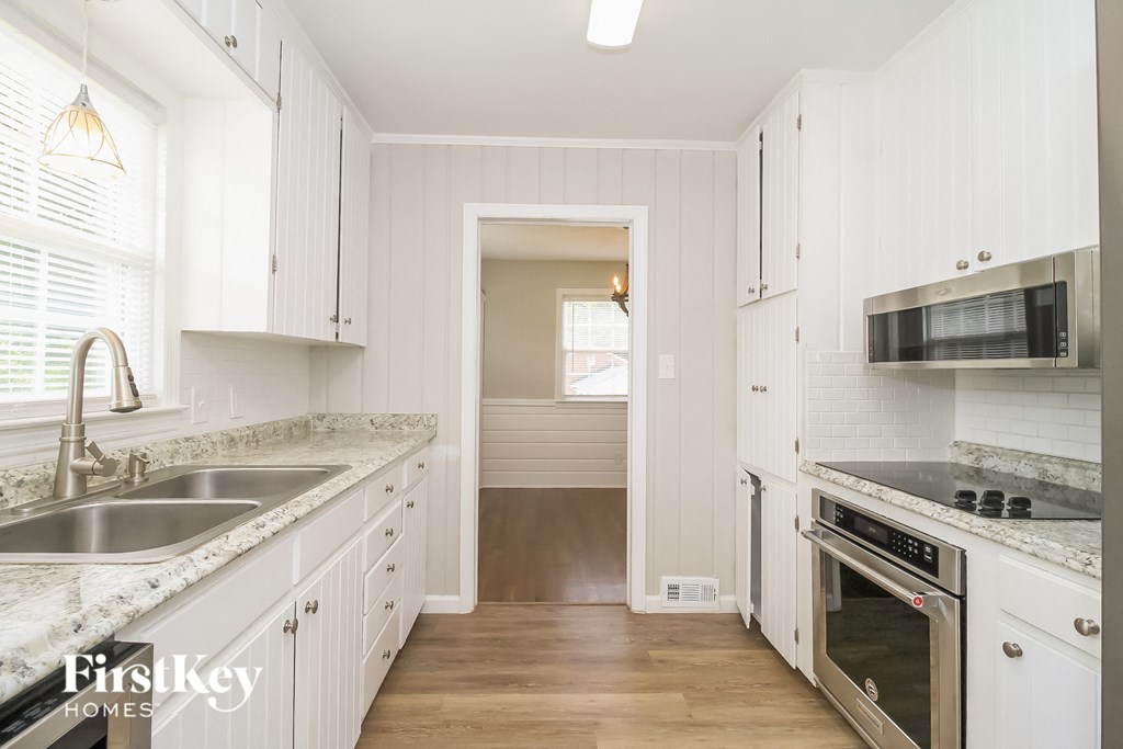 a kitchen with white cabinets and a sink and a stove