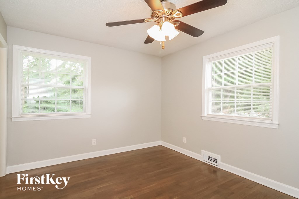 a bedroom with a ceiling fan and two windows