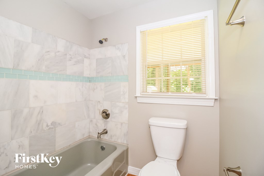 a bathroom with a toilet and a tub and a window