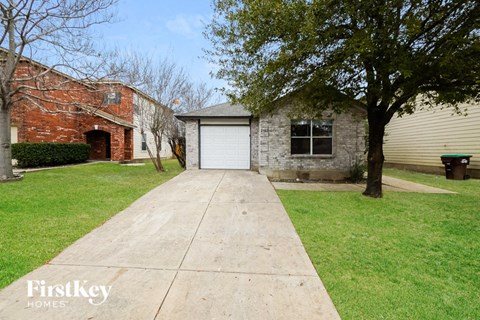 A house with a garage and a tree in front.