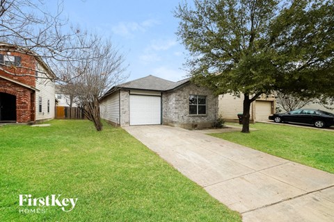 A house with a garage and a tree in front of it.