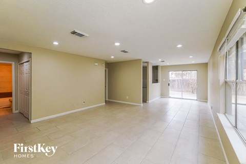 A spacious room with a tiled floor and a sliding glass door leading to a balcony.
