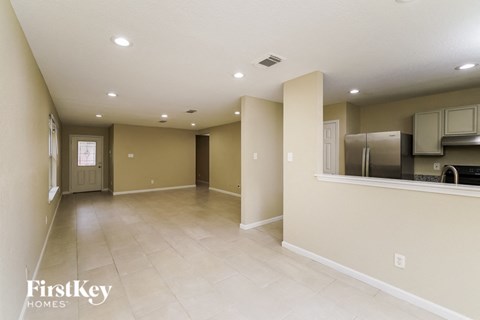 A spacious room with a kitchen area in the background.