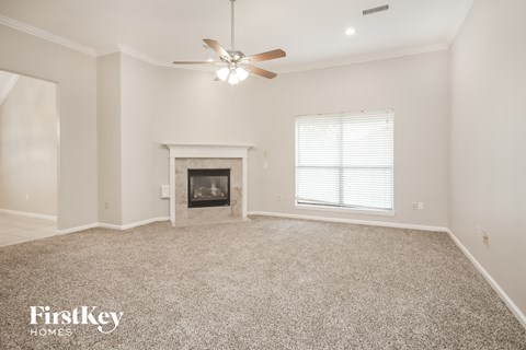 the spacious living room with fireplace and ceiling fan