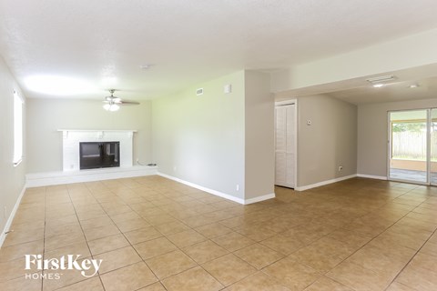 A spacious room with a fireplace and tiled flooring.