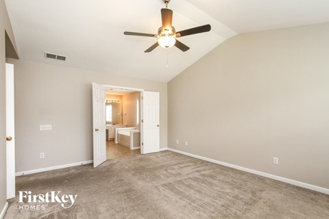 a spacious living room with carpet and a ceiling fan