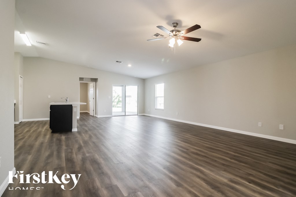 an empty living room with wood floors and a ceiling fan