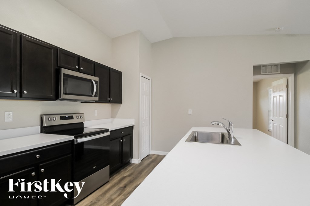 a kitchen with black cabinets and white counter tops and a sink