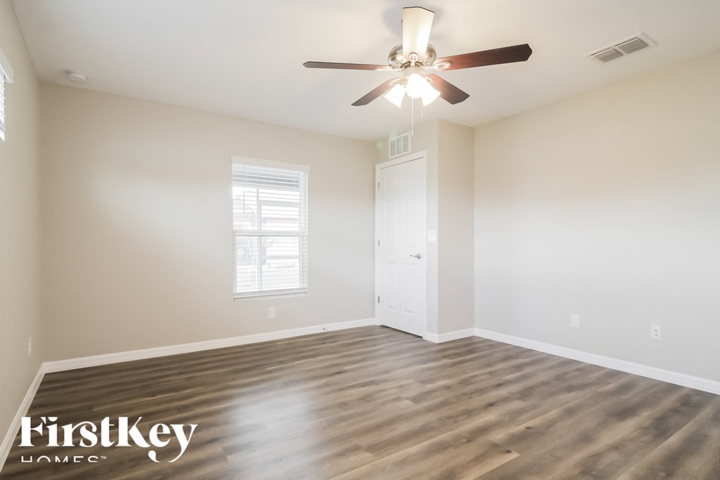 an empty living room with wood floors and a ceiling fan