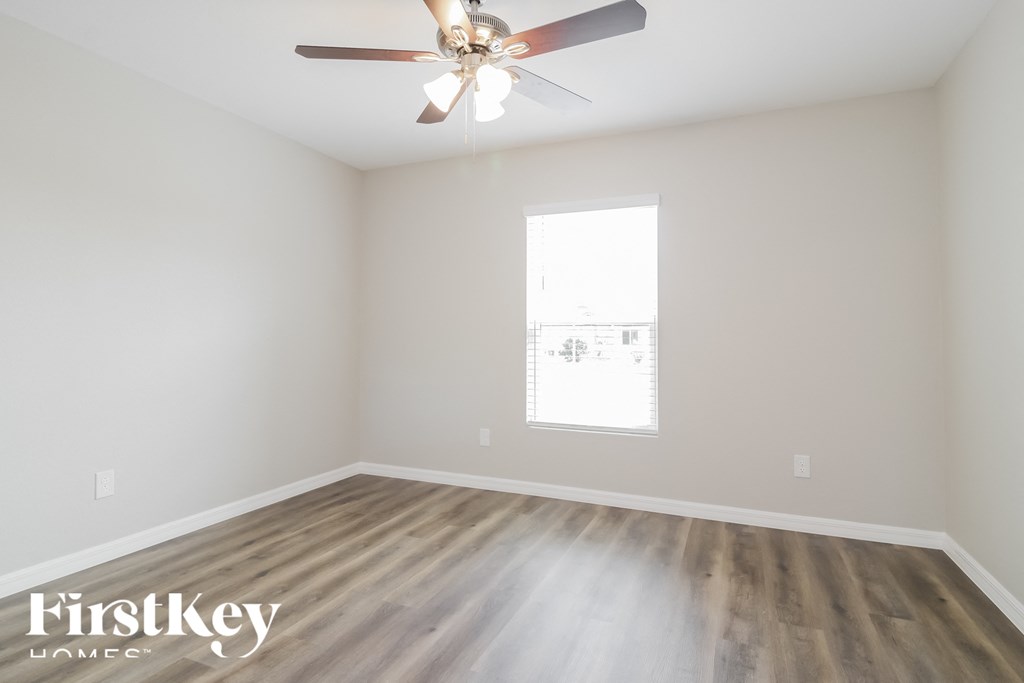 an empty room with a ceiling fan and a window