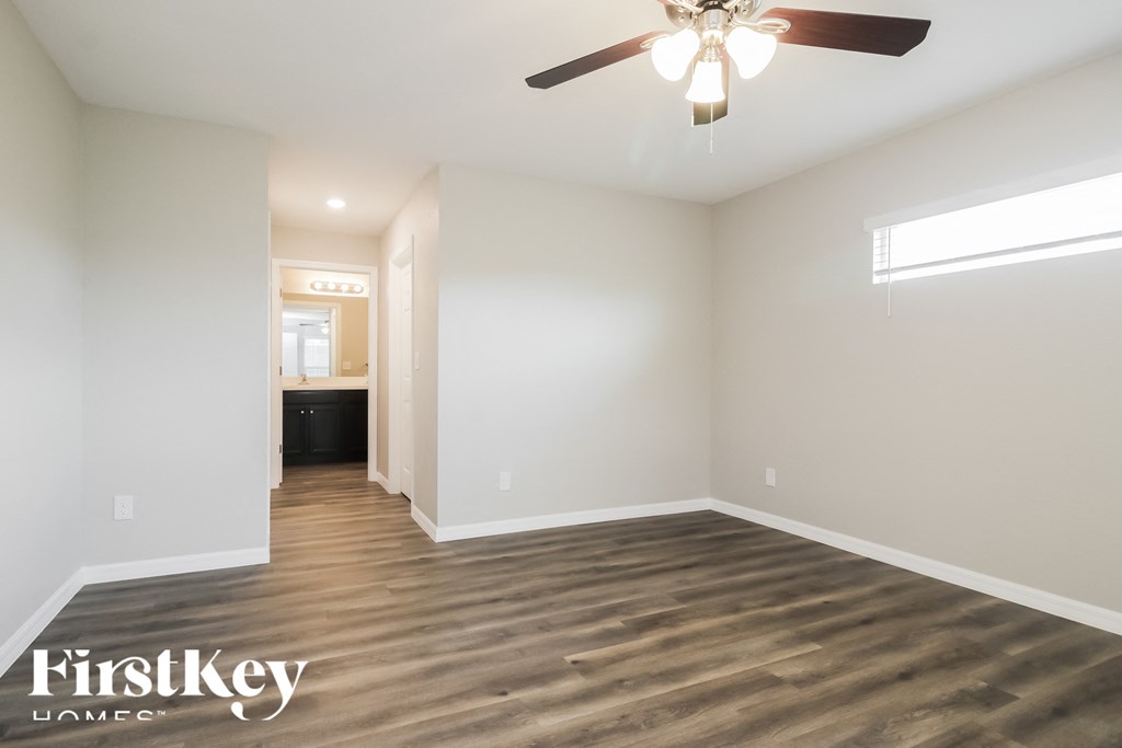 an empty living room with wood flooring and a ceiling fan