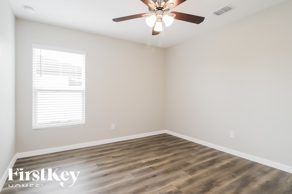 an empty room with a ceiling fan and a window