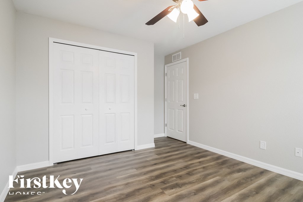 the living room of a new home with white walls and a ceiling fan