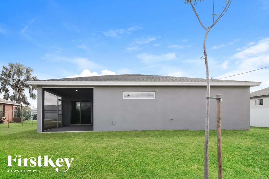a small gray house with a grass yard and a blue sky