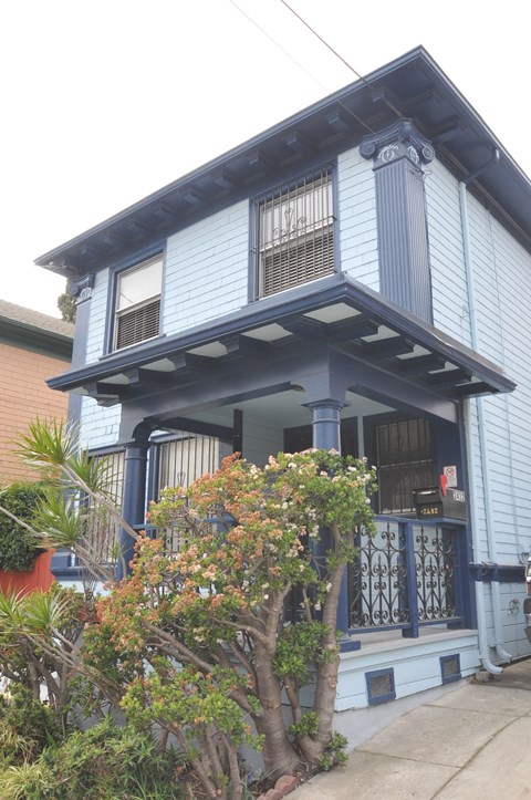 A blue house with a tree in front.