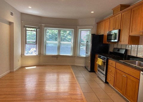 A kitchen with wooden cabinets and a black refrigerator.