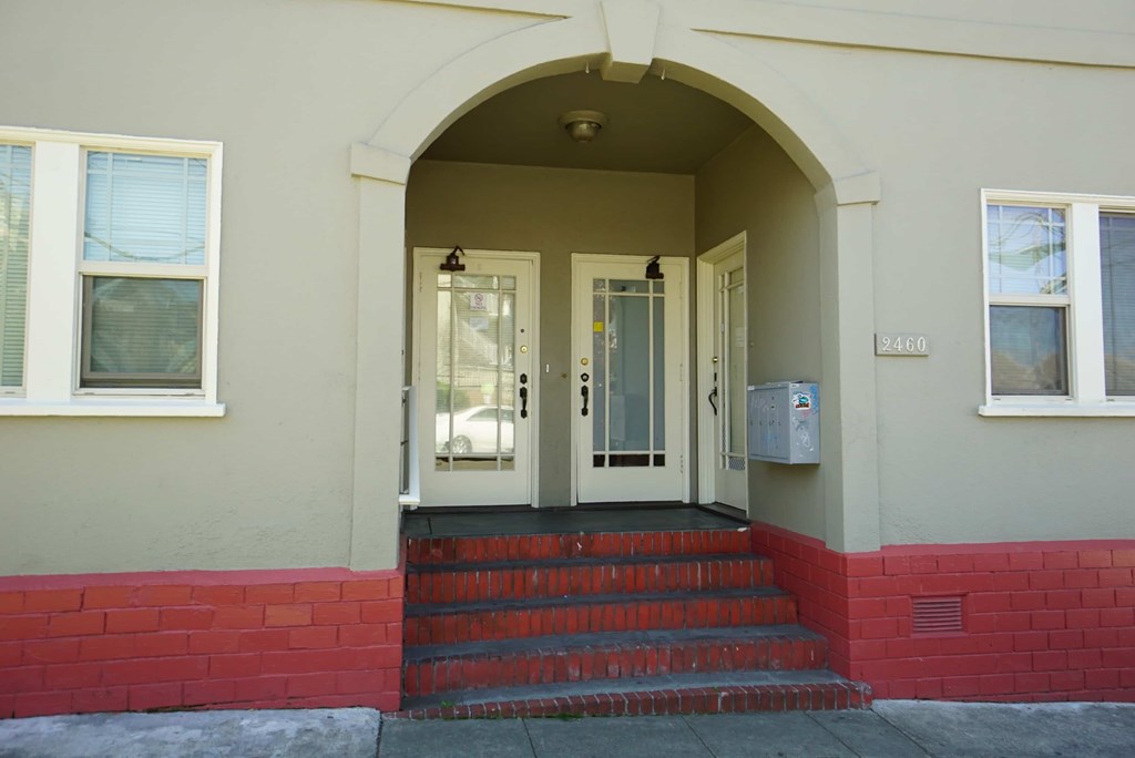 the front entrance of a building with a red staircase
