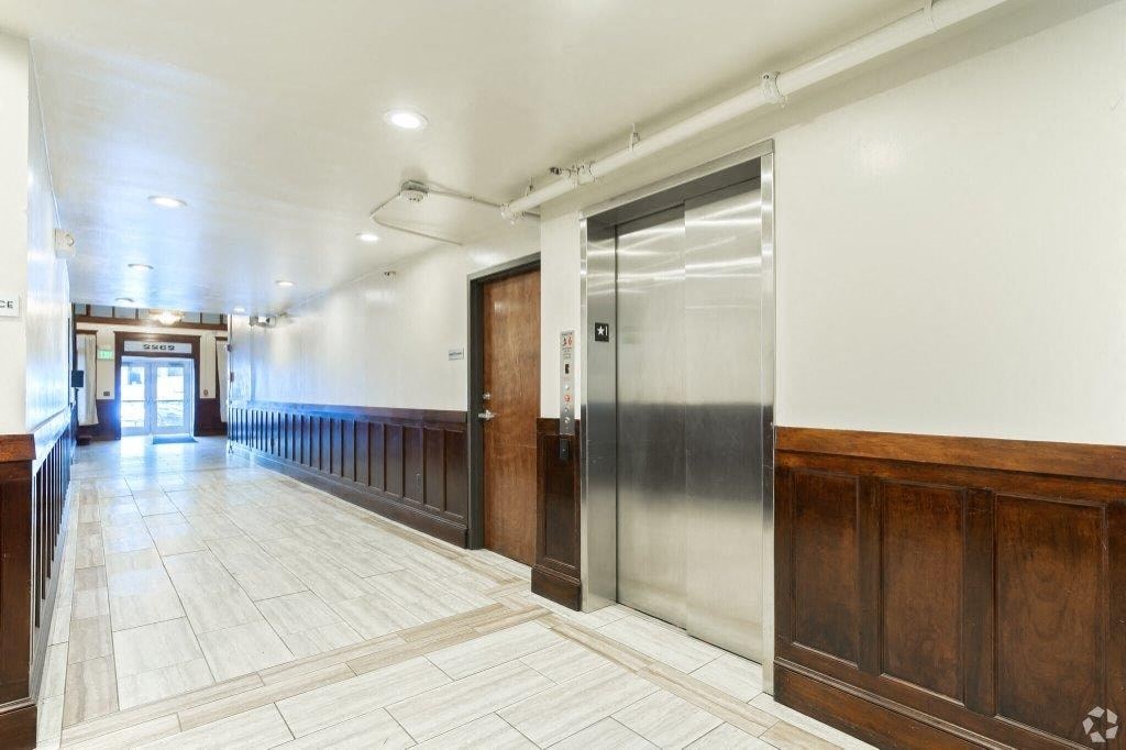 the lobby of a building with two elevators and a hallway with wood paneling
