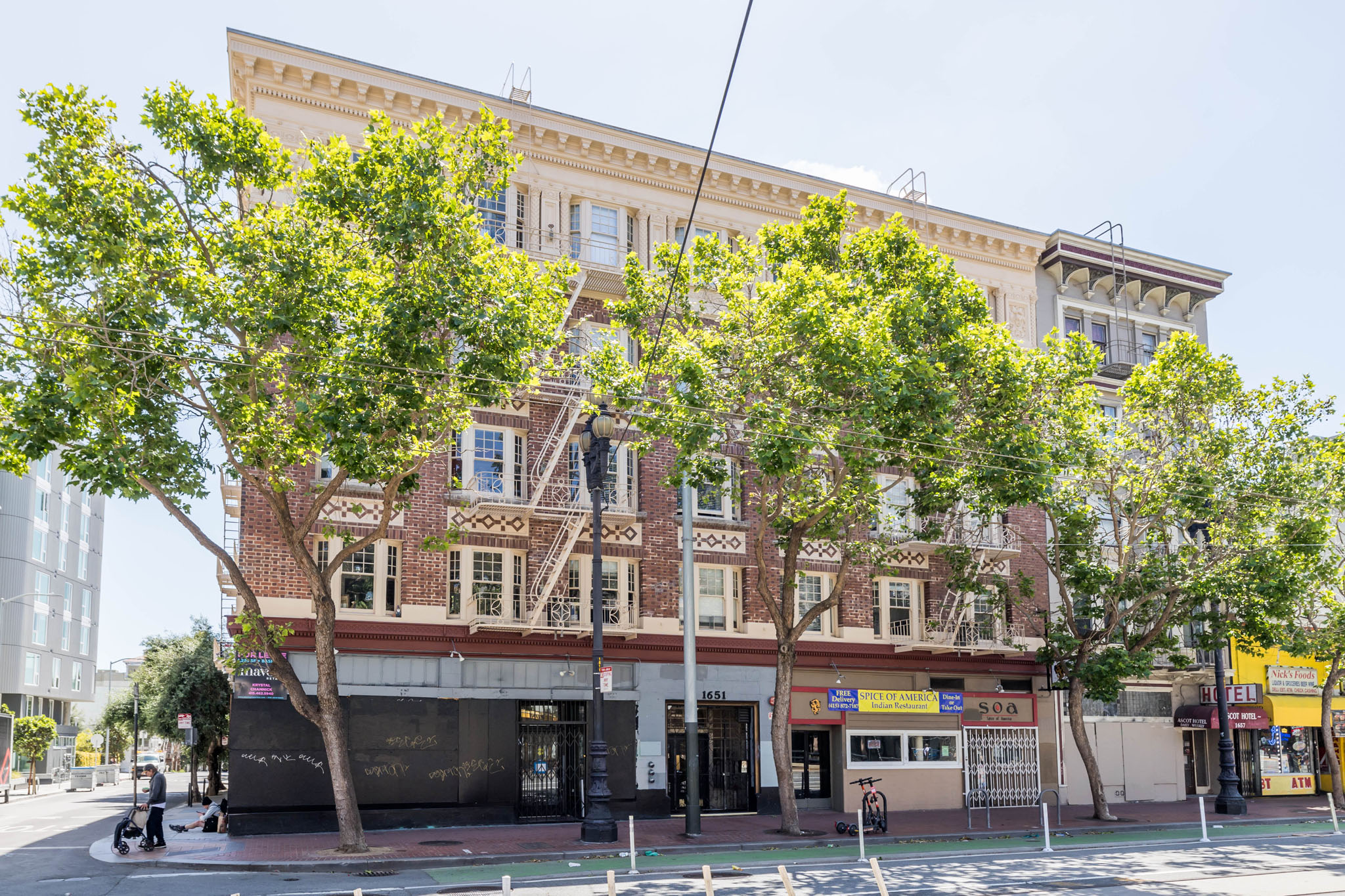 A large building with a balcony on the second floor is surrounded by trees.
