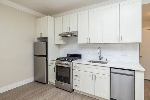 A kitchen with white cabinets and a stainless steel refrigerator.