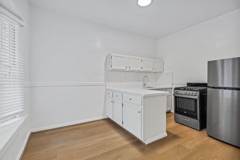 A kitchen with white cabinets and a stainless steel refrigerator.