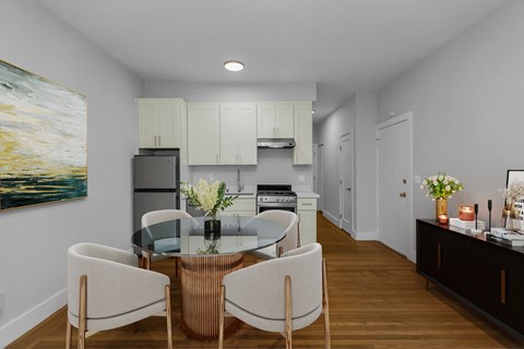 A modern kitchen with a glass dining table and chairs.