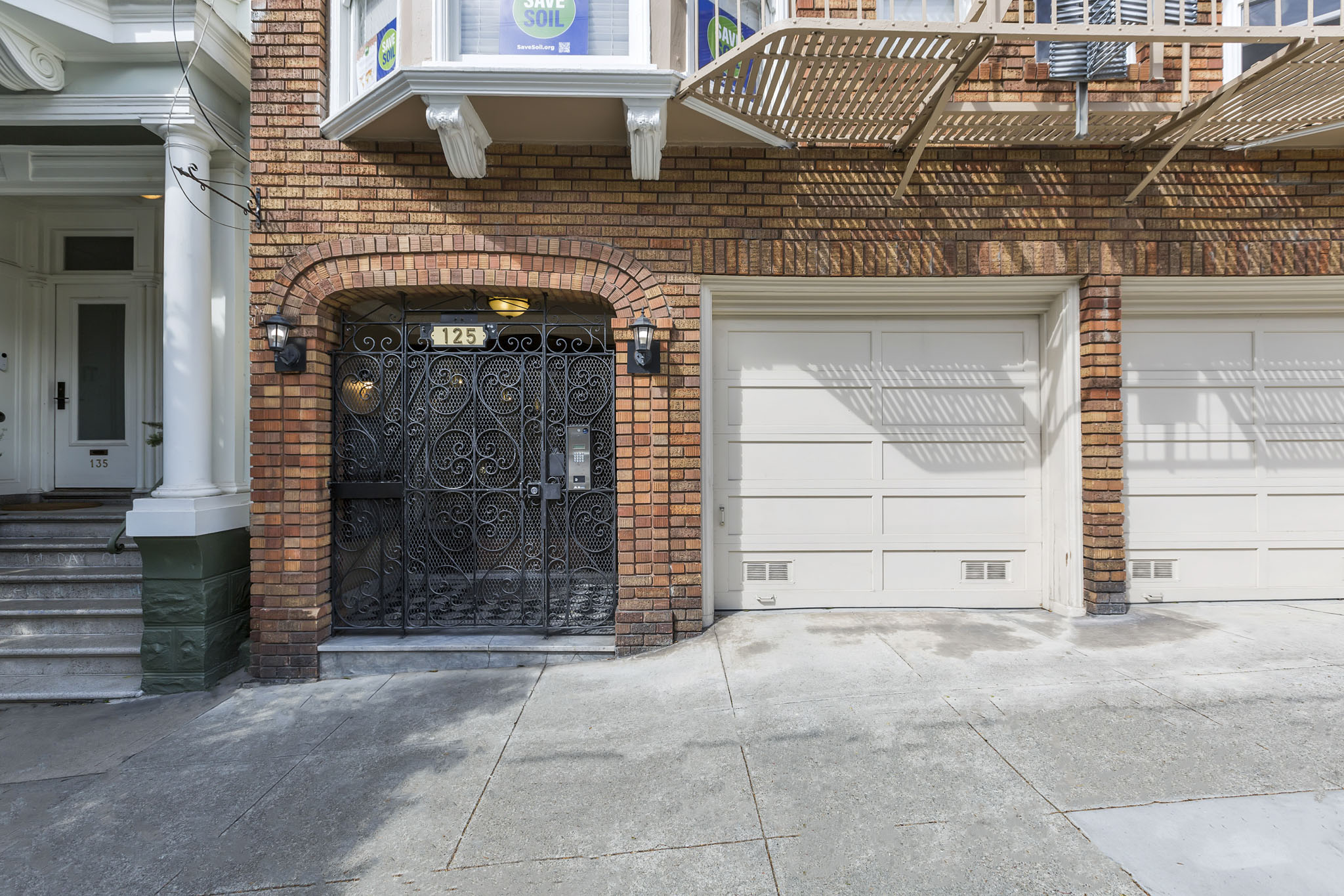 A black wrought iron gate is on the left side of a brick building.