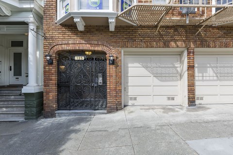 A black wrought iron gate is on the left side of a brick building.