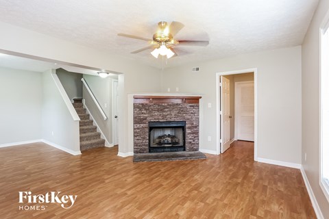 A living room with a fireplace and a staircase.