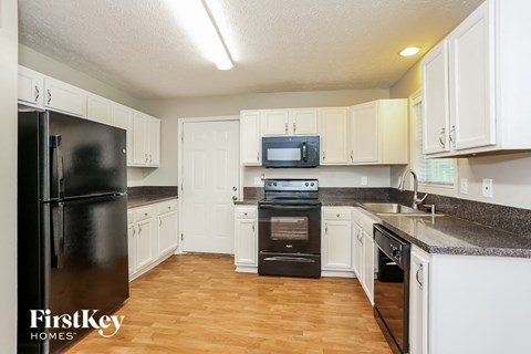 A kitchen with a black refrigerator and white cabinets.