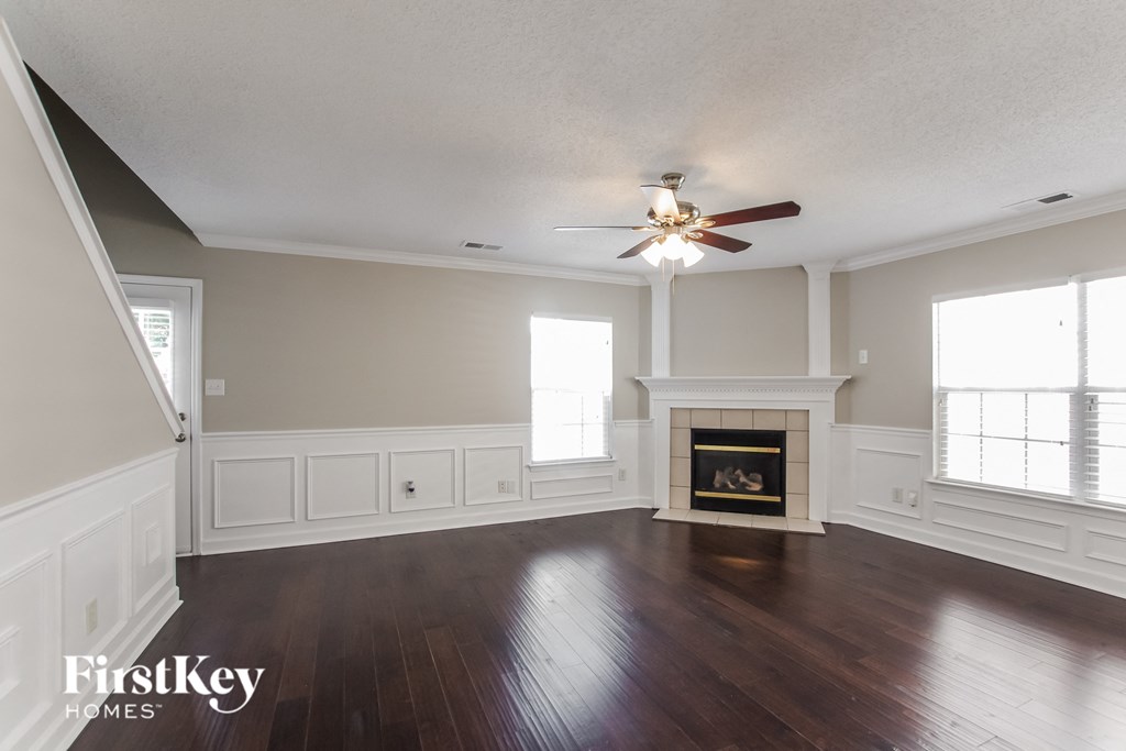 A spacious room with a fireplace and a ceiling fan.
