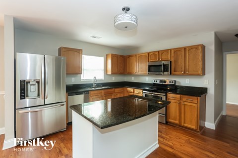 A kitchen with a black granite counter top and wooden cabinets.