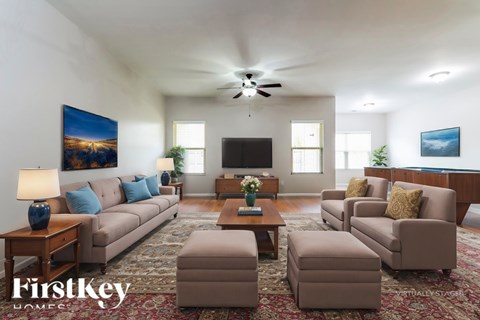 A well-lit living room with a beige sofa set and a painting on the wall.