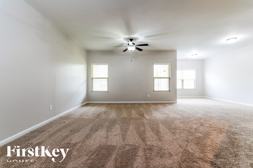 A spacious room with a carpeted floor and a ceiling fan.