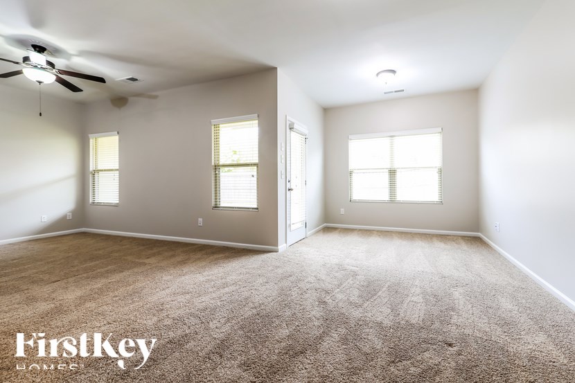 A spacious room with a carpeted floor and a ceiling fan.