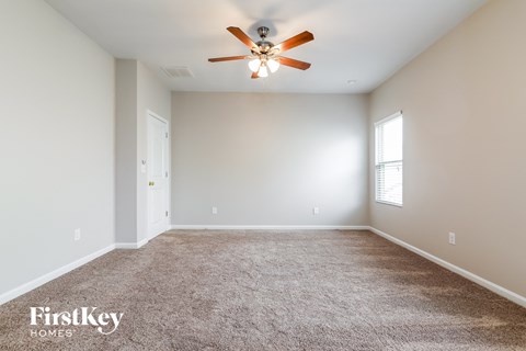 a spacious living room with carpet and a ceiling fan