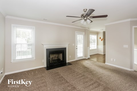 A living room with a fireplace and a ceiling fan.