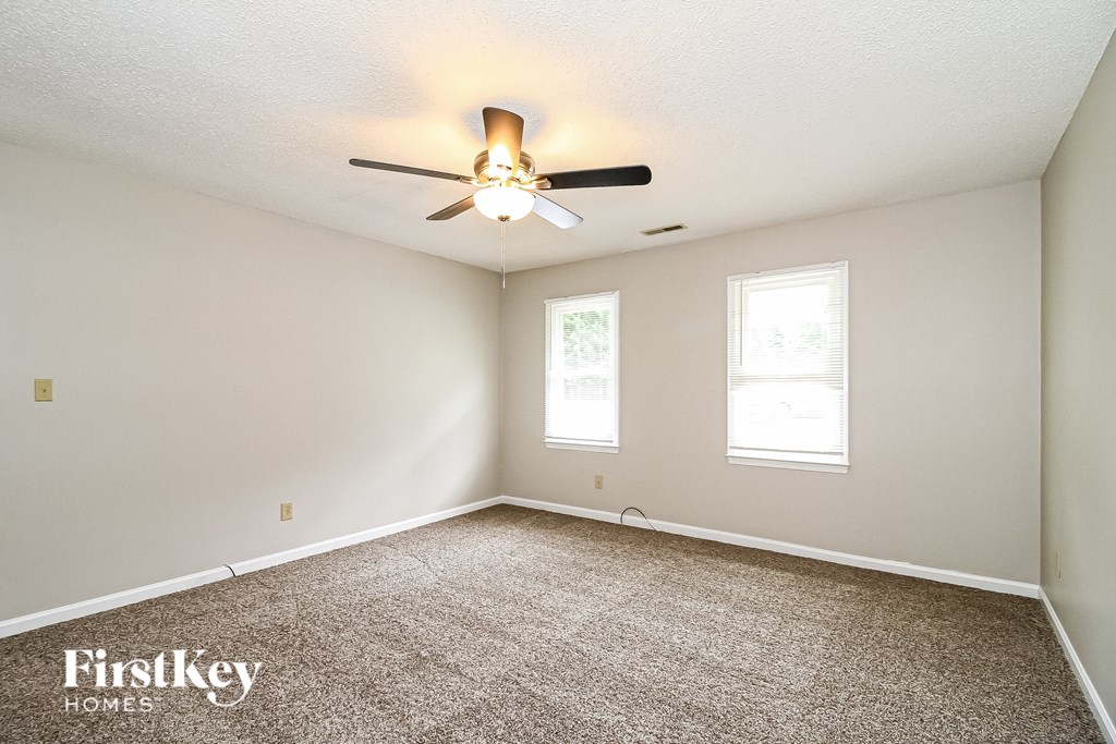 the master bedroom has a carpeted floor and a ceiling fan
