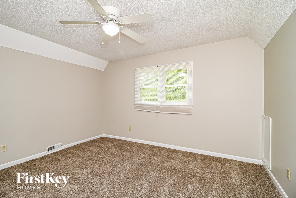 the bedroom of a rental house with a carpeted floor and a ceiling fan