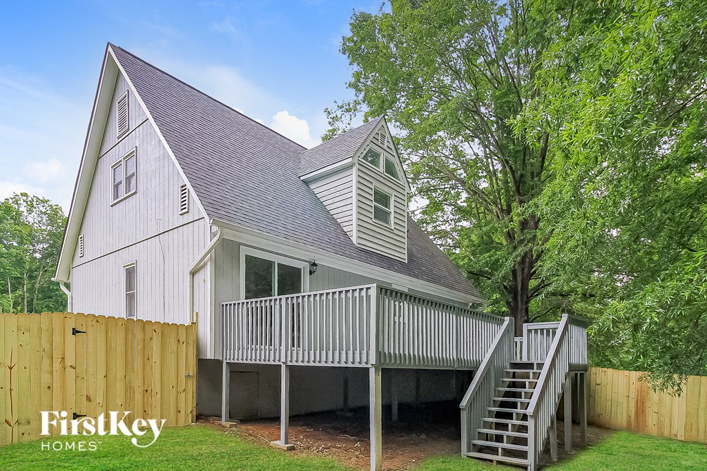 a white cottage with a deck and a wood fence
