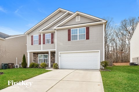 a beige house with a white garage door and a green lawn