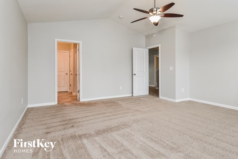 a spacious living room with carpet and a ceiling fan