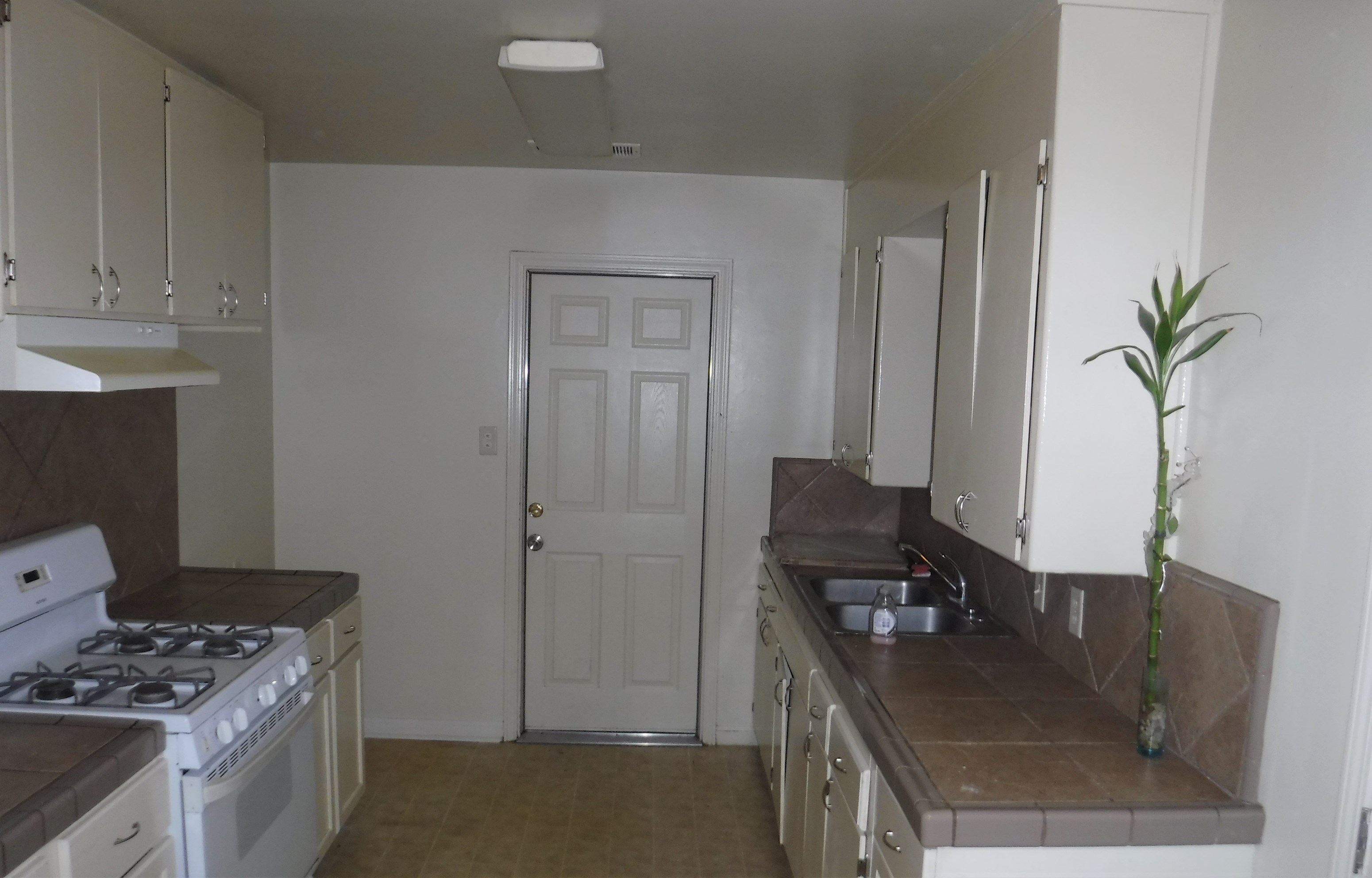 an empty kitchen with white appliances and a white door