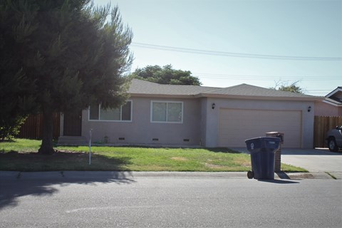 a house with a trash can on the curb in front of it