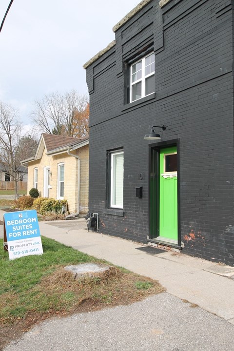 a black house with a green door and a sign on the sidewalk