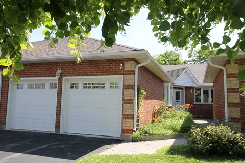 A house with a white garage door is seen through the leaves.